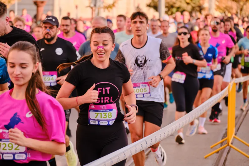 A smiling woman in a black running shirt approaching the camera.