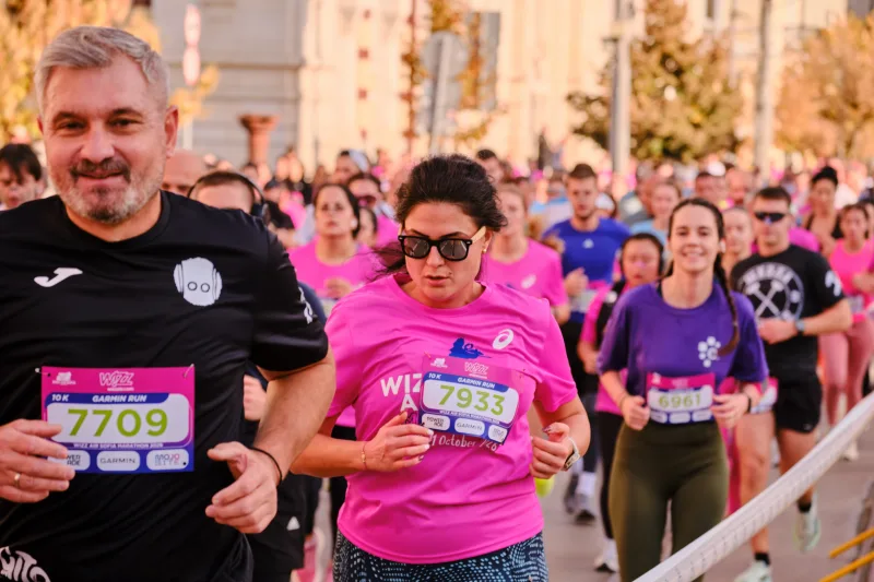A smiling runner in black beside a participant wearing sunglasses.