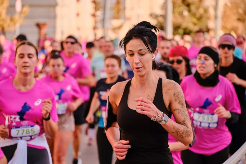 A woman in a black running vest approaching through the crowd.