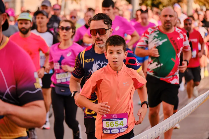 A young runner in an orange polo shirt approaching through the crowd.