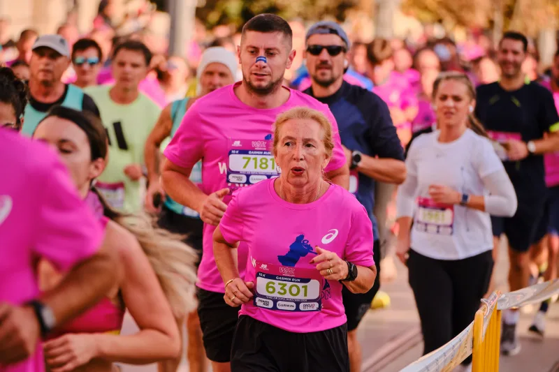 A woman in pink approaching ahead of the running field.