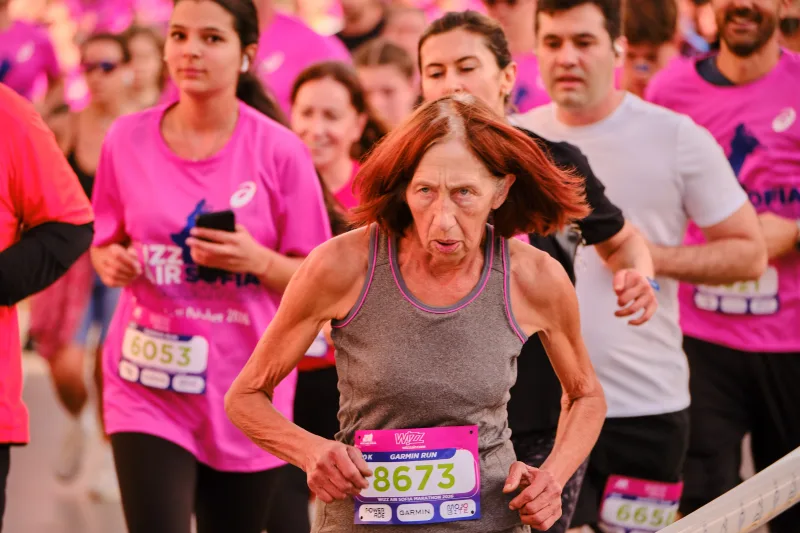 A runner in a grey sleeveless top with red hair flying behind her.