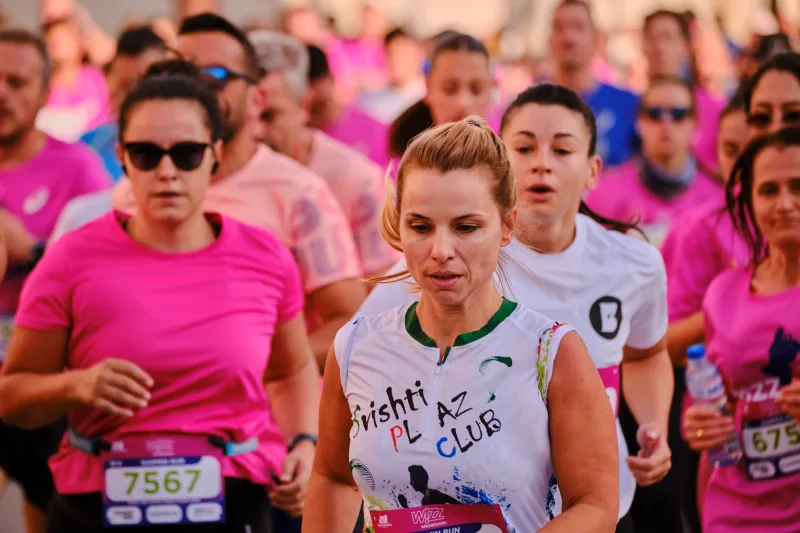 A woman in a pale sleeveless shirt approaching among runners in pink.