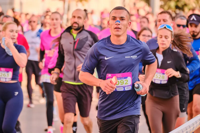 A runner in navy approaching ahead of participants in black and pink.