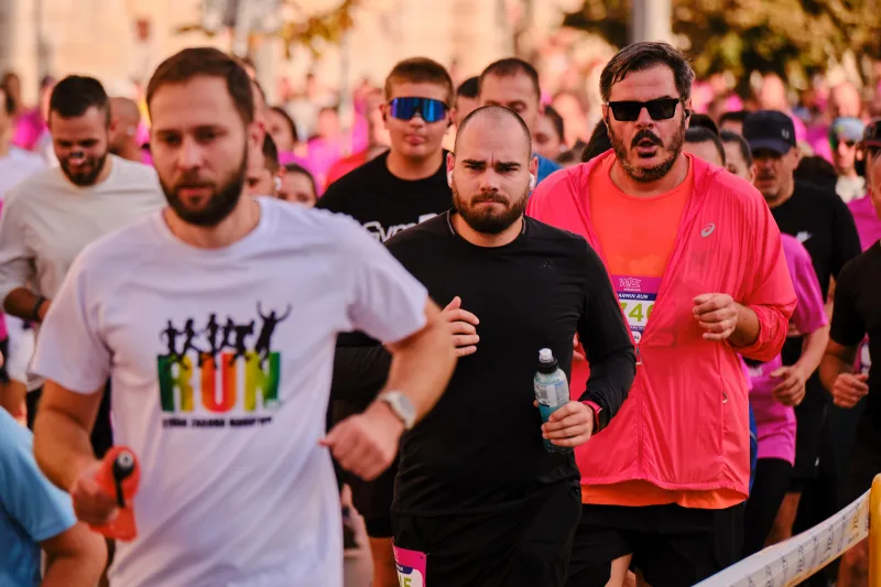 Runners in white, black and red shirts moving together along the route.