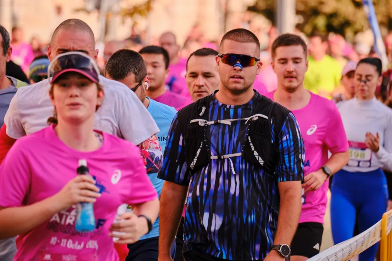 A runner in a patterned blue shirt and cap among the crowd.