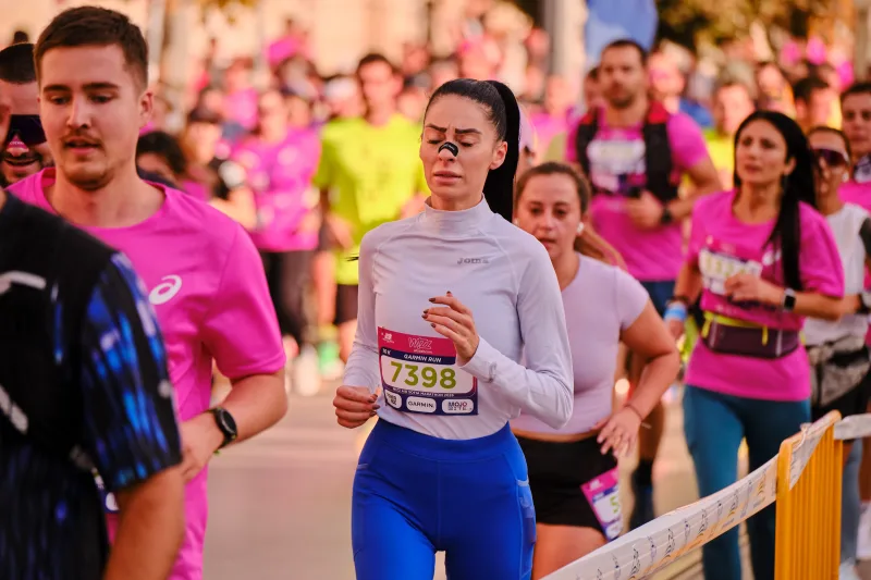 A woman in a pale long-sleeved top and blue leggings approaching.