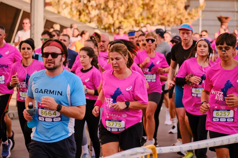 A runner in a blue shirt, sunglasses and headphones moving through the field.