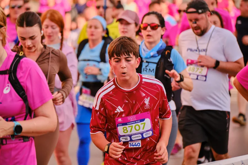 A young runner in a red patterned sports shirt approaching the camera.