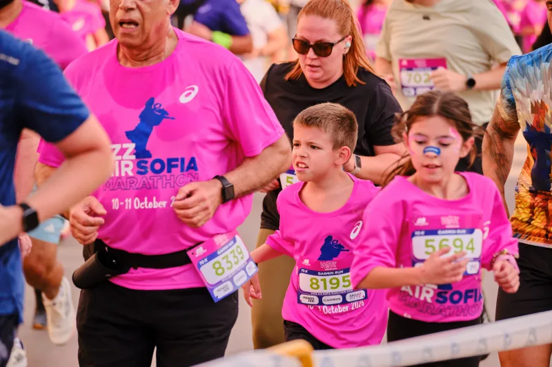 Young participants in pink event shirts and face paint running together.