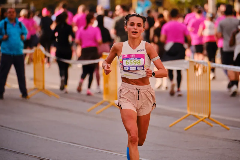 A runner in a white top and pale peach shorts approaching down the street.