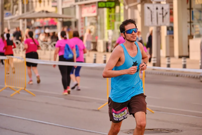 A runner in a turquoise vest and mirrored sunglasses on the open road.