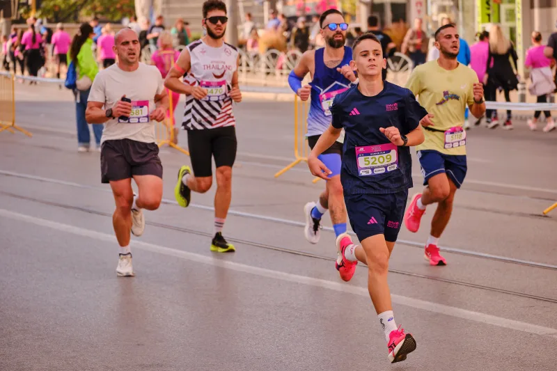 A woman in navy running ahead of participants in pale and yellow tops.