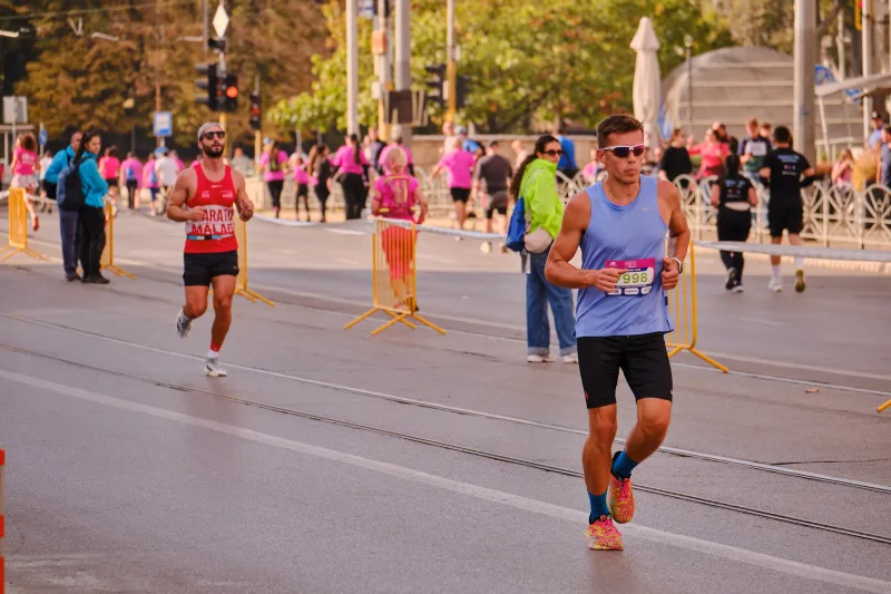 A runner in a blue vest approaching along the tram tracks.