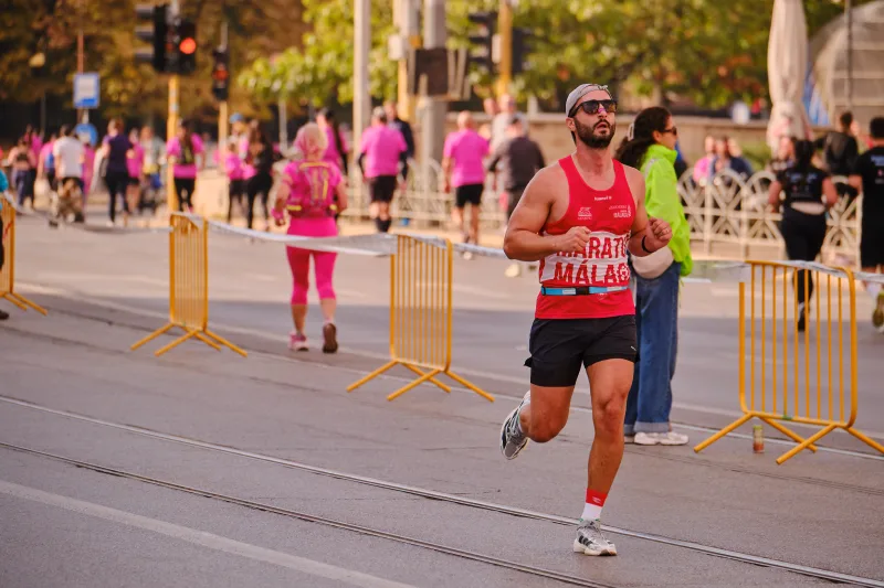 A runner in a red sleeveless top, black shorts and sunglasses.