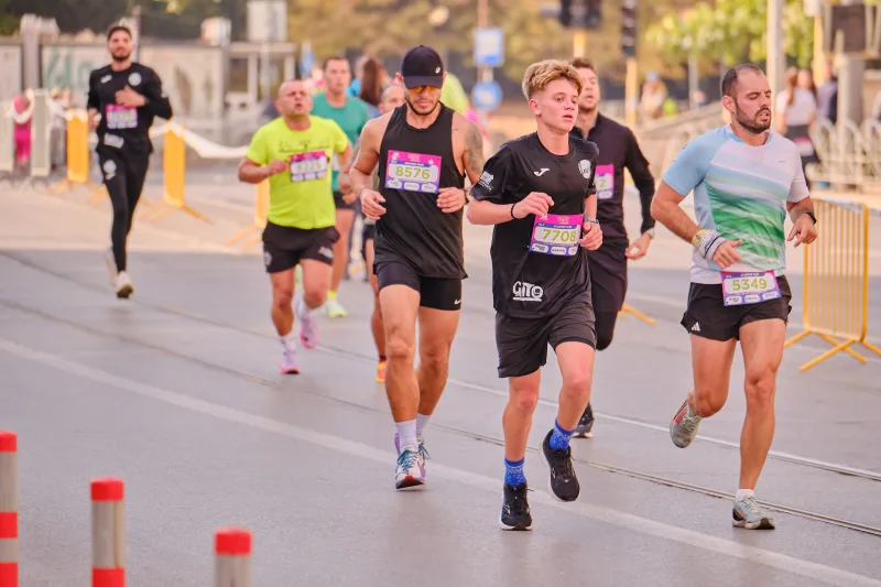 A woman in a black shirt and shorts among a small group of runners.