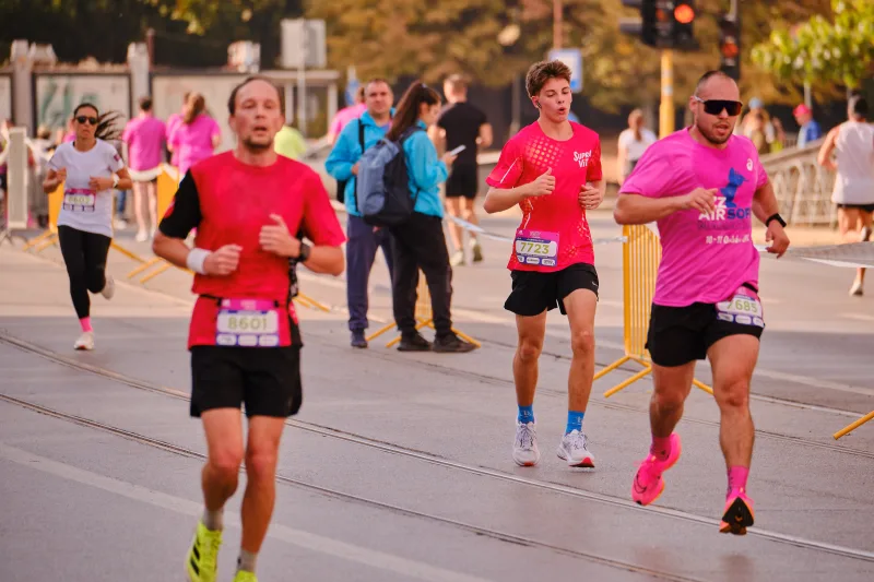 Two participants in red shirts running along the street.