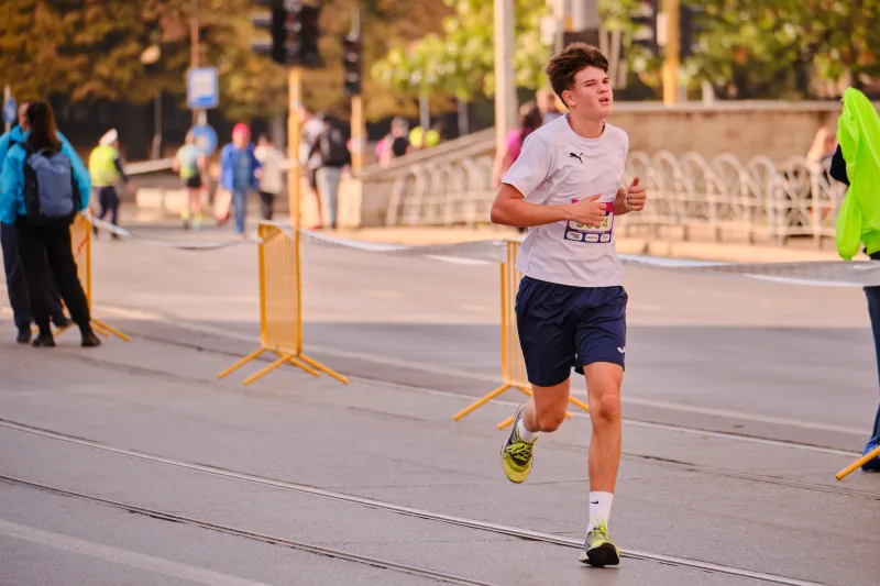 A young participant in a pale shirt and navy shorts on the open road.