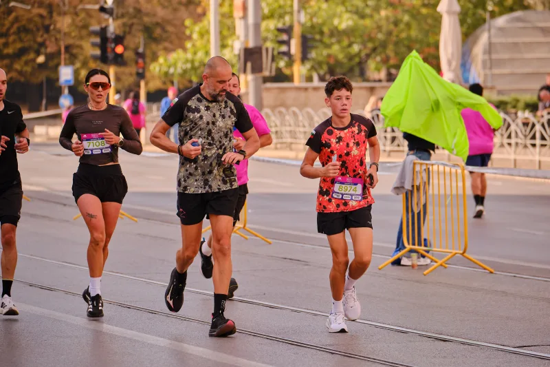 A man and a young participant in patterned dark and red shirts running together.