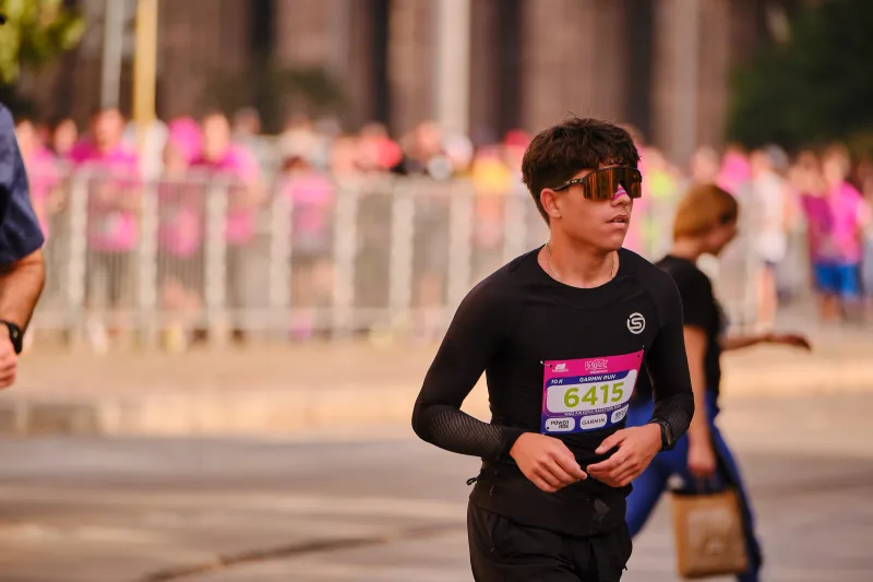 A young runner in a black long-sleeved top looking to the side.