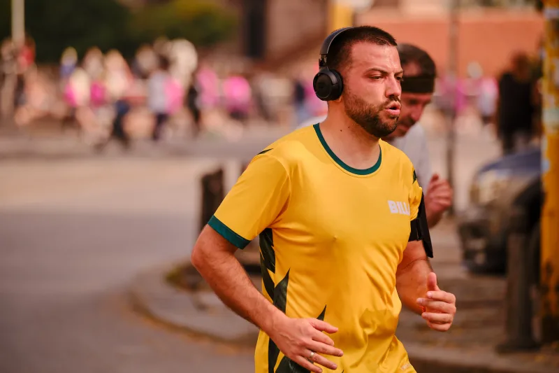 A close view of a runner in yellow wearing black headphones.