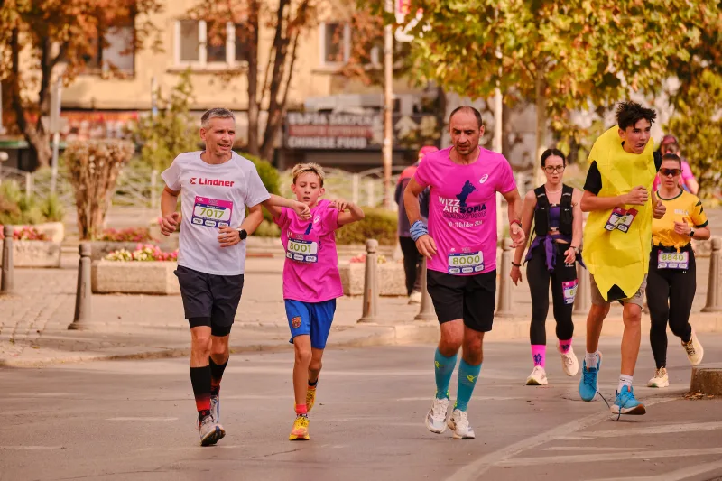A young participant in pink and blue shorts running among adults.