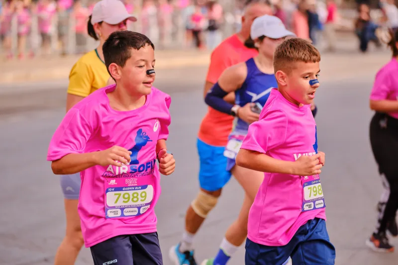 Two young participants in pink shirts running side by side.